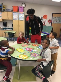 students playing a number matching game with a Learning Center student teacher