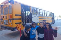 students posing in front of a school bus