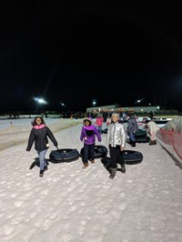 students carrying their snow tubes up the hill